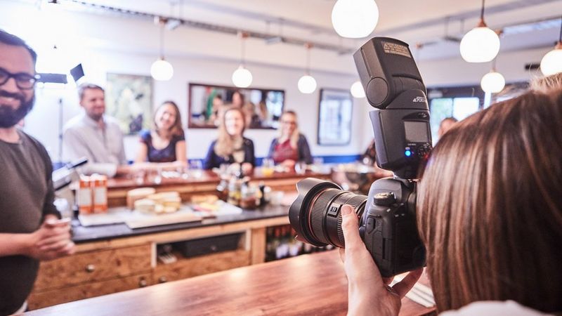 Female taking a group picture in a restaurant with a Canon 6D Mark II + Canon Speedlite 470EX-AI